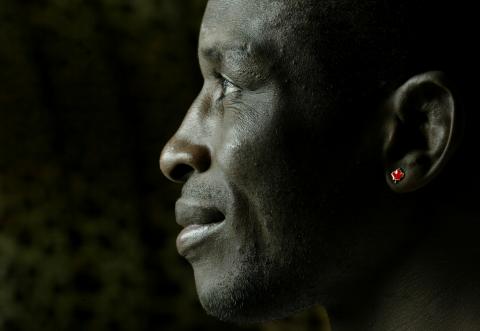 Profil en gros plan de Daniel Igali portant une boucle d’oreille rouge en forme de feuille d’érable du Canada.