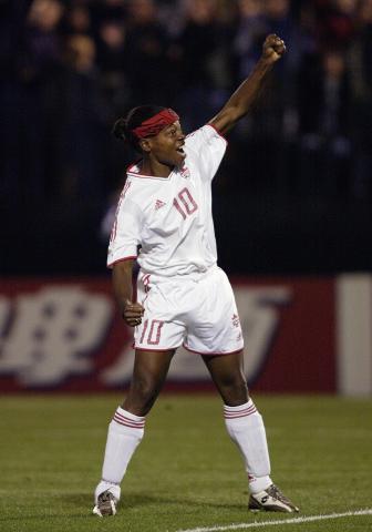 Charmaine Hooper revêtue de blanc, le bras levé, sur un terrain de soccer.