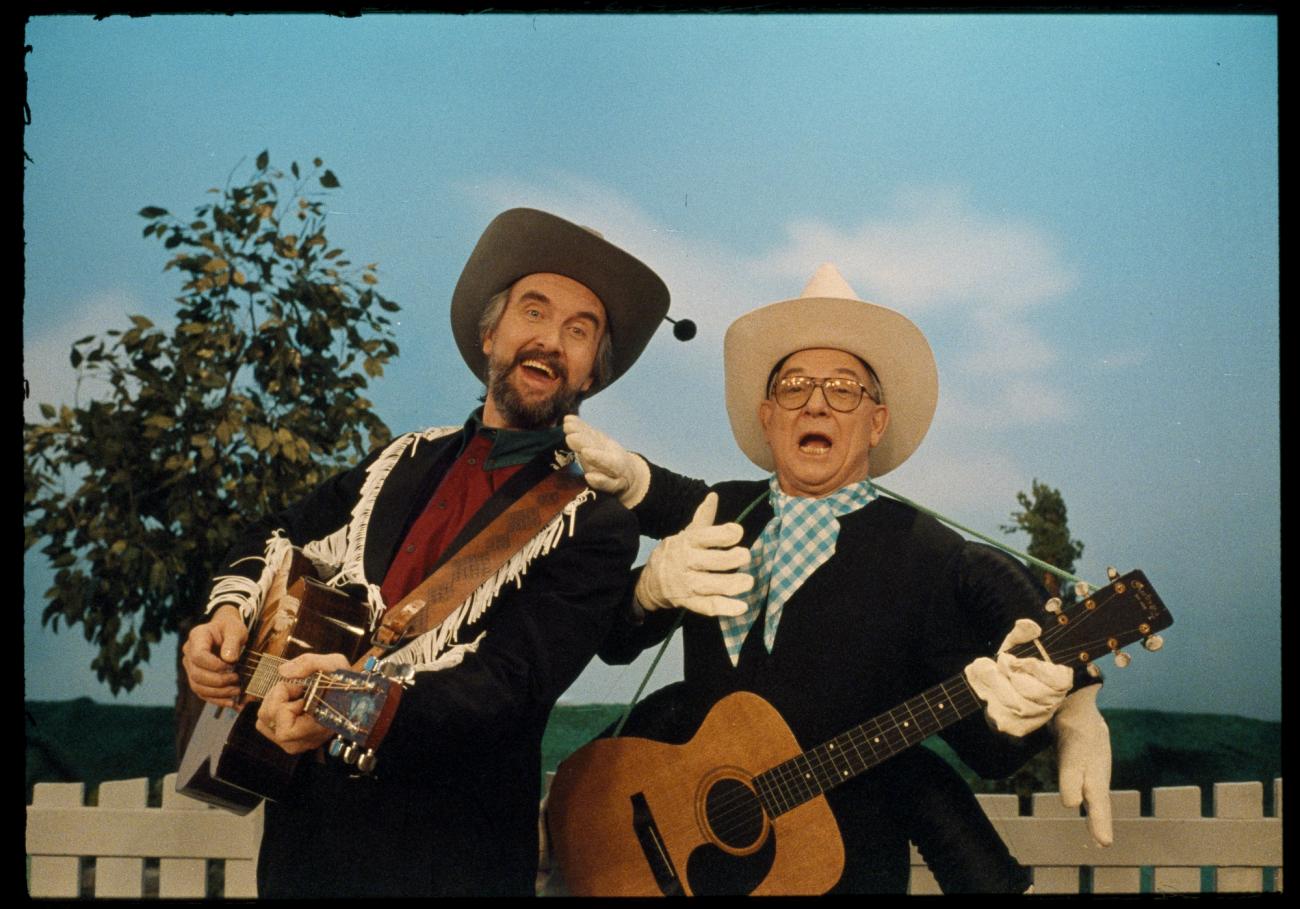 Ernie Coombs et un autre homme, la guitare à la main, tous deux portant un Stetson et en tenue de style western.