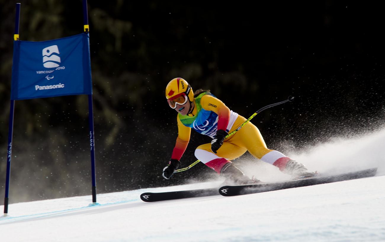 Karolina Wisniewska habillée en jaune skiant vers un drapeau bleu.