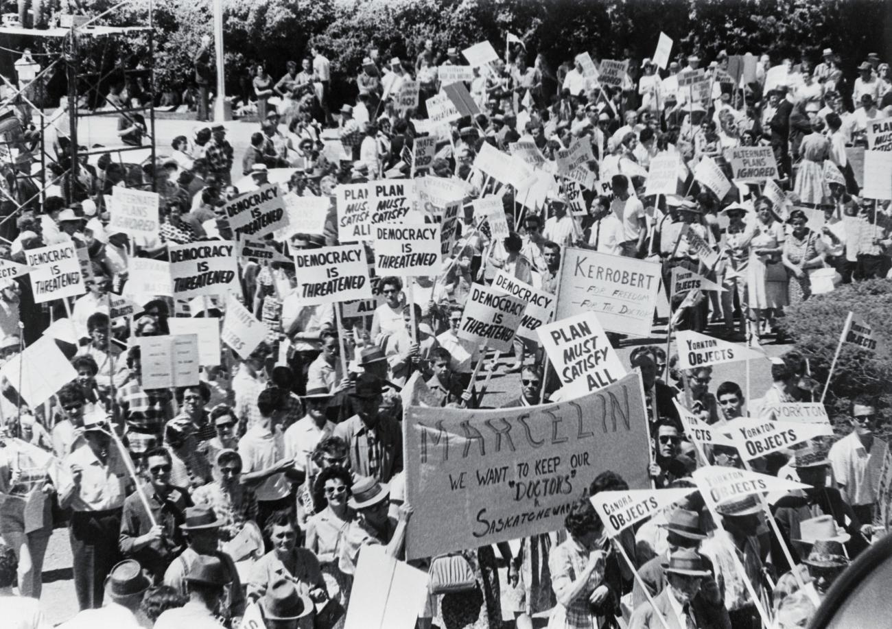 Photo en noir et blanc de nombreux manifestants tenant des panneaux et des bannières.