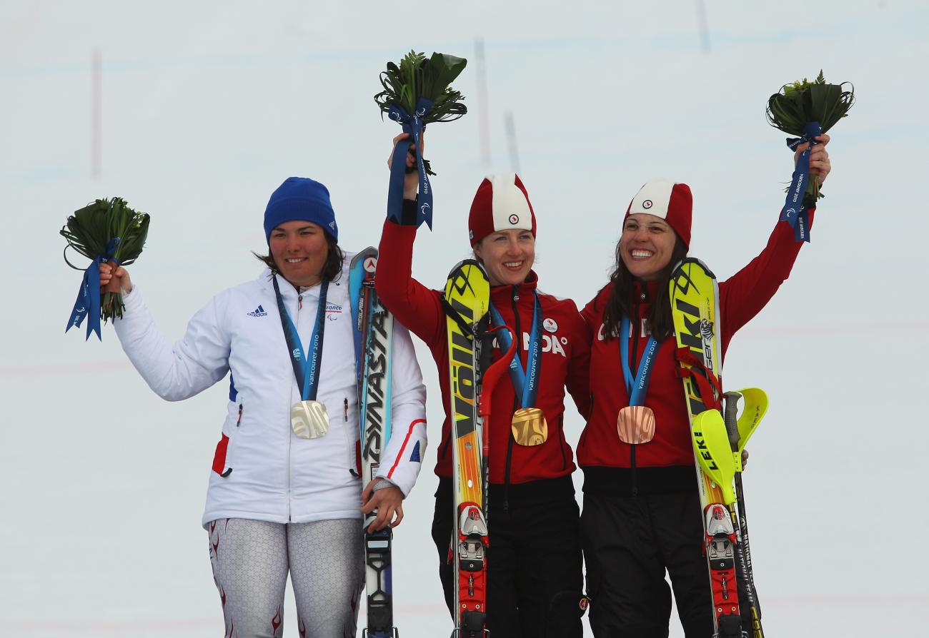 Karolina Wisniewska en uniforme rouge avec une femme en rouge et une autre femme en blanc, toutes portant une médaille et un bouquet.
