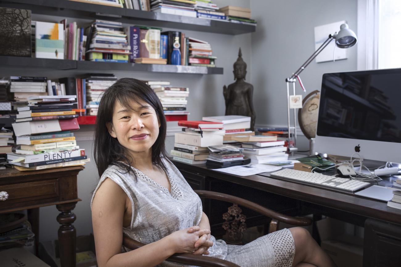 Kim Thúy Ly Thanh assise à un bureau, des étagères de livres derrière elle.
