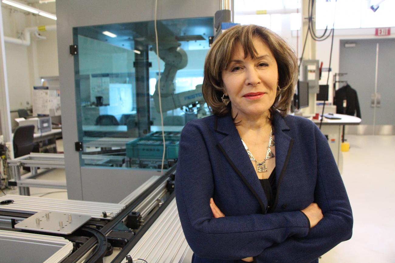 Hoda ElMaraghy, en veste bleue foncée, debout dans un laboratoire scientifique.