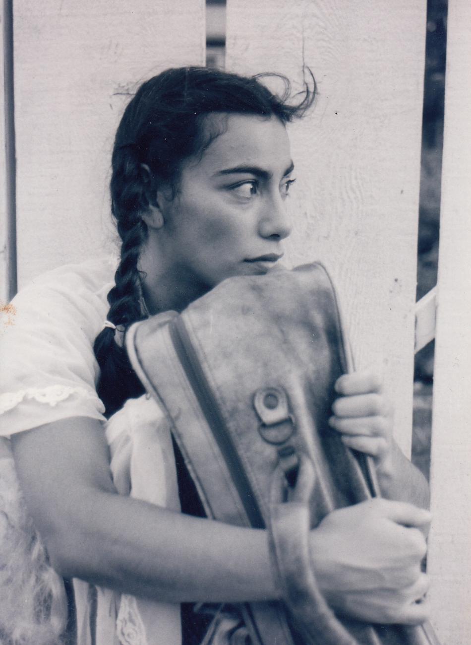 Carmen Aguirre avec des tresses, assise et serrant une valise dans ses bras.