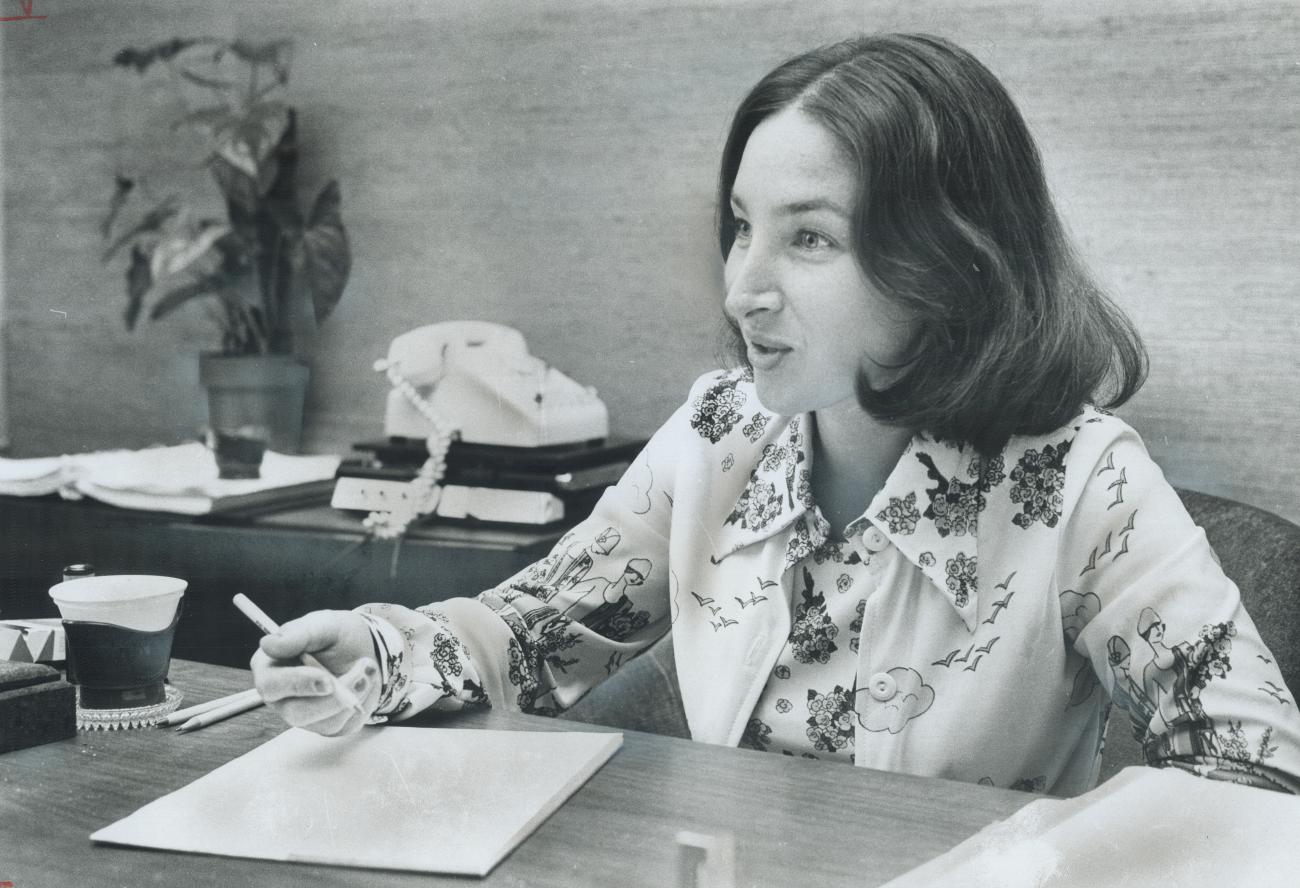 Une femme assise à un bureau avec un stylo à la main et du papier devant elle.