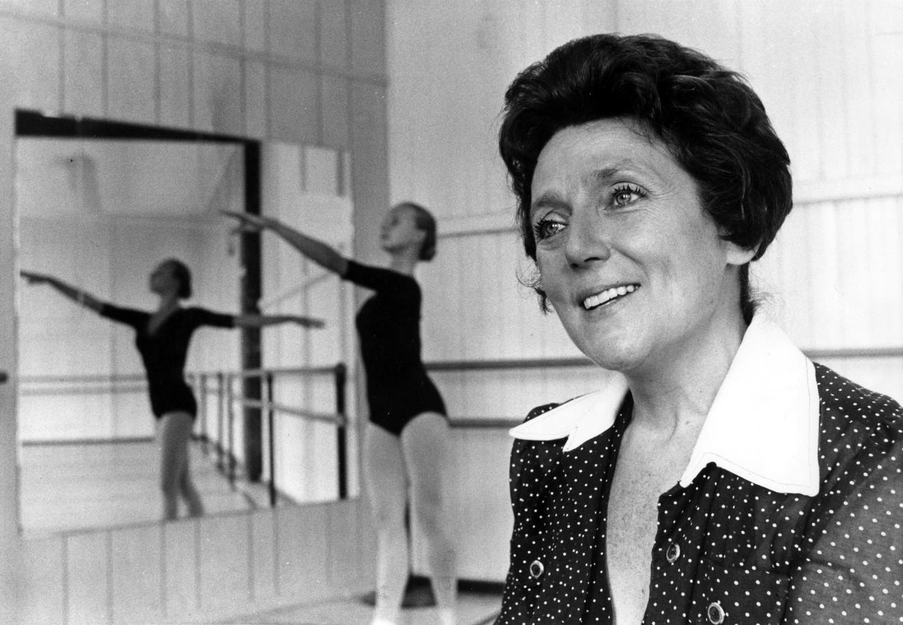 Portrait de Ludmilla Chiriaeff dans un studio de danse avec une danseuse en arrière-plan.